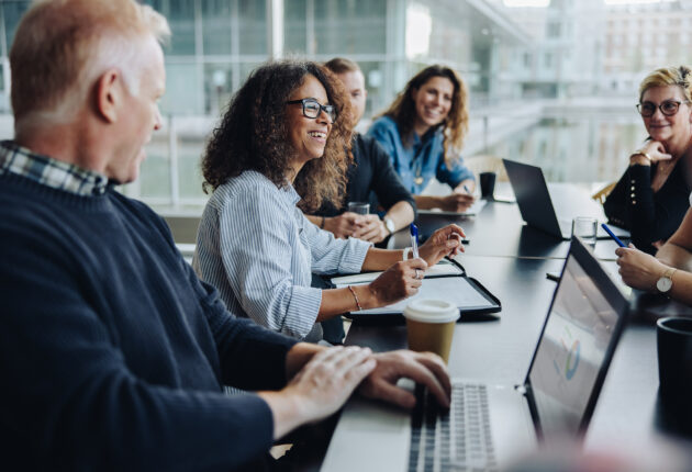 Multi-ethnic business people smiling during a meeting in conference room. Team of professionals having meeting in boardroom.