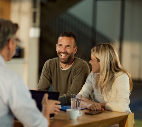 Young happy couple communicating with their agent during a meeting in the office. Focus is on man.